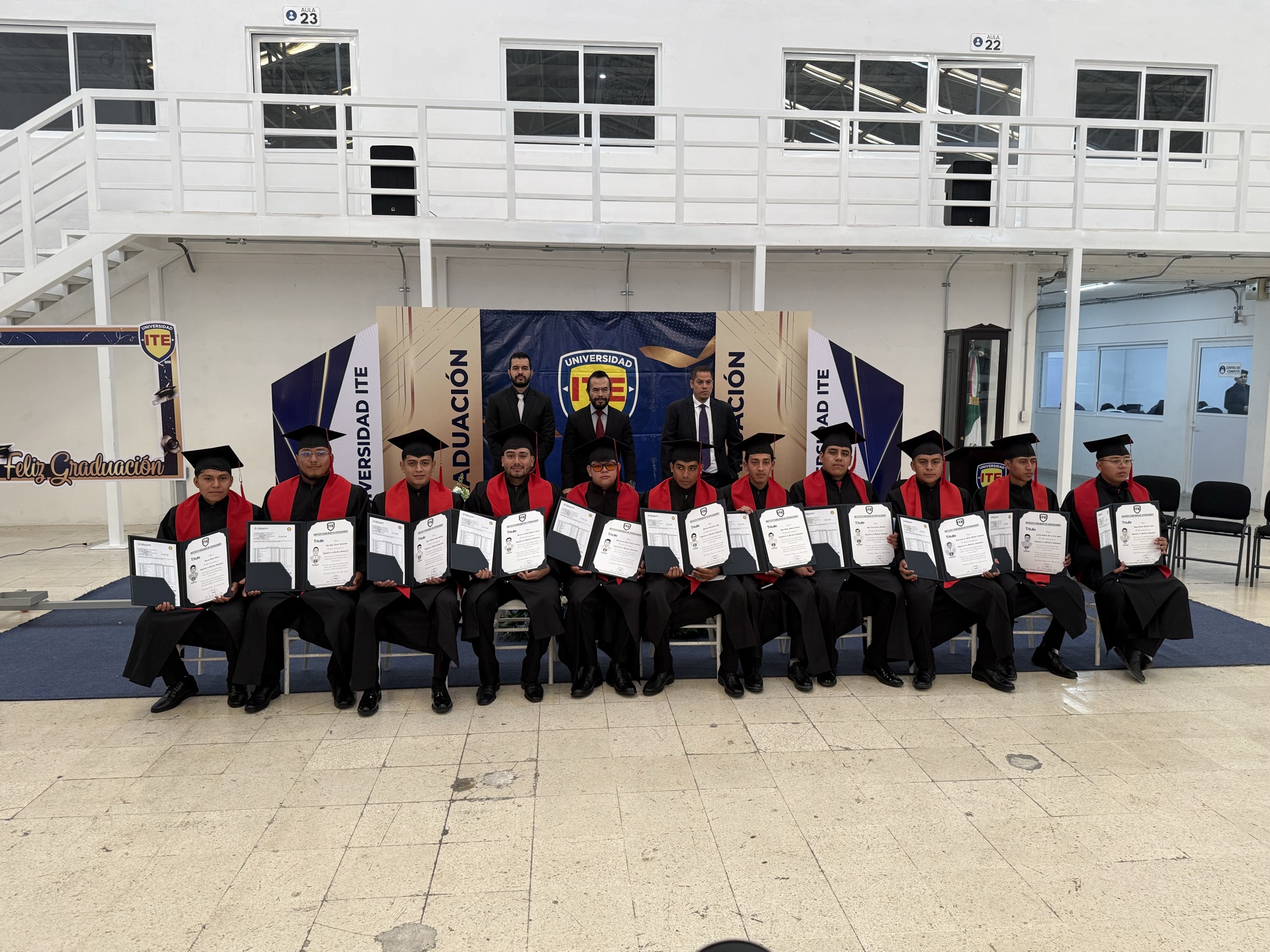 Generación de egresados de Universidad ITE mostrando sus documentos